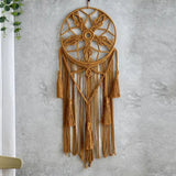 attrape rêve fait main - attrape-rêve en macramé ocre à fleur nouée et cinq glands, accroché à un mur gris