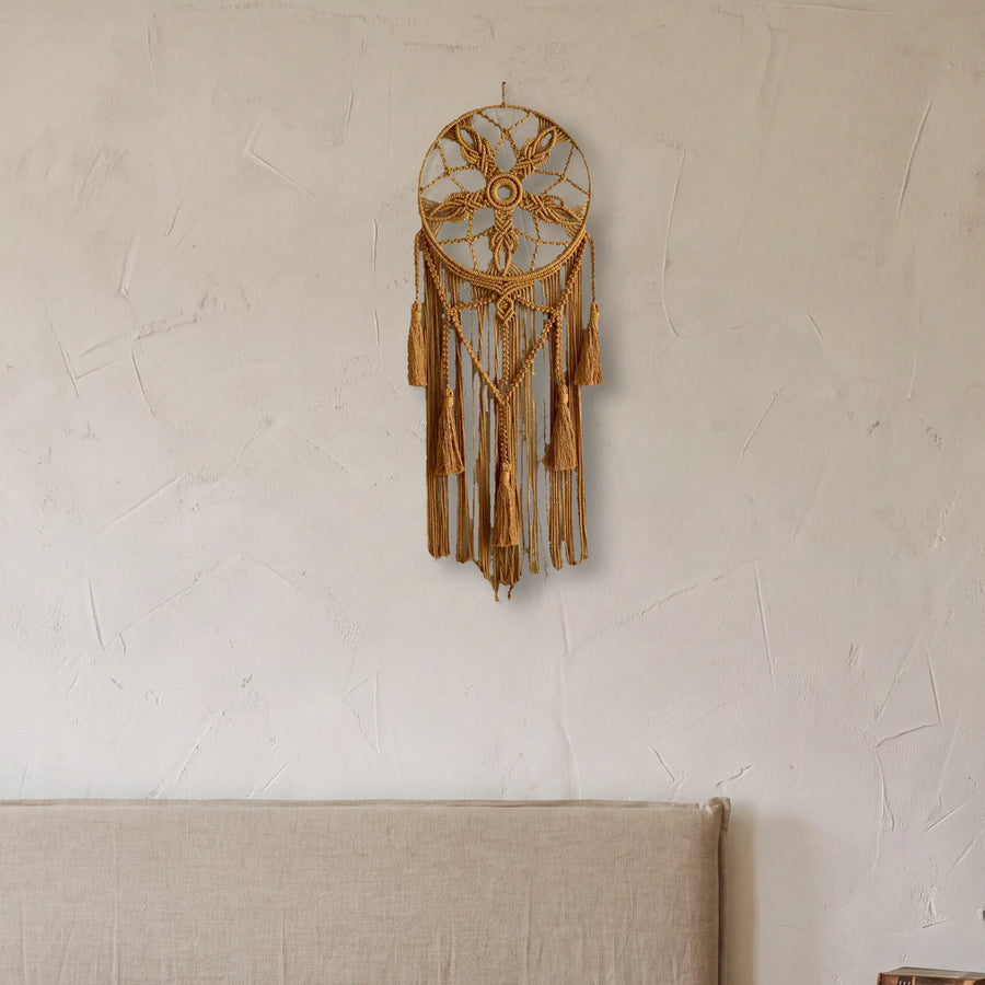 attrape rêve macramé ocre à fleur et glands, accroché au mur d'une chambre à la chaux