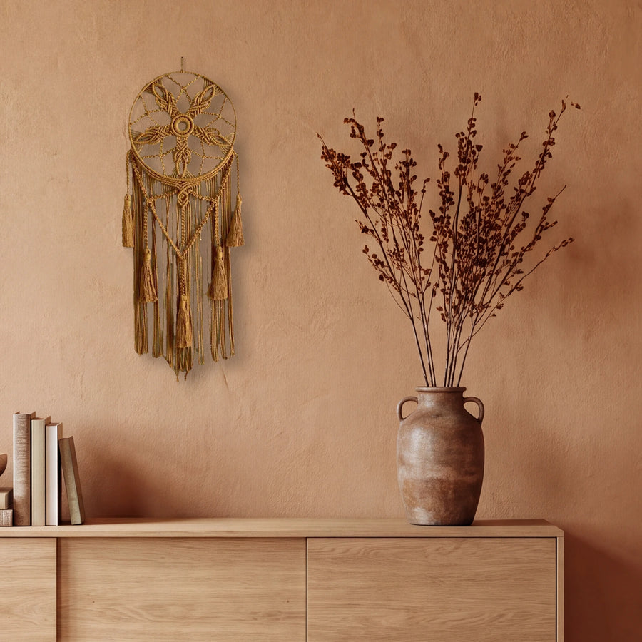 attrape rêve macramé ocre à fleur et glands, accroché au mur terracotta d'un salon, au-dessus d'un buffet en bois