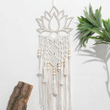 attrape rêve macramé - lotus et perles de bois accroché sur un mur blanc