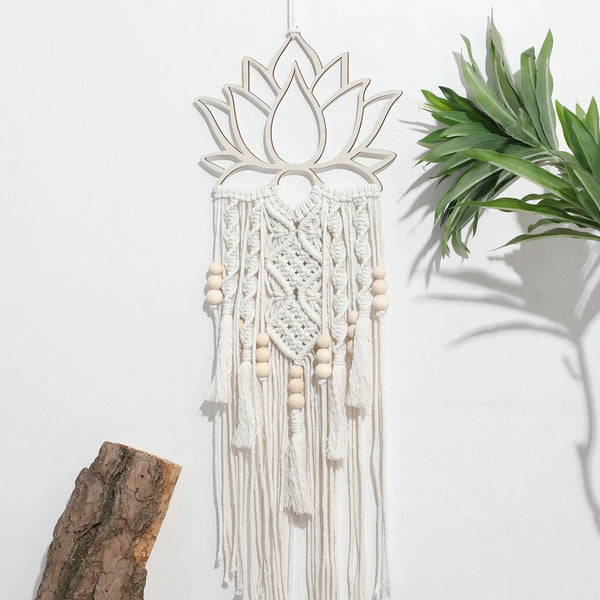 attrape rêve macramé - lotus et perles de bois accroché sur un mur blanc