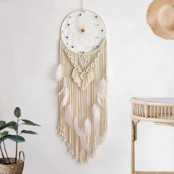 attrape rêve macramé - attrape-rêve en macramé écru, plumes blanches et perles, accroché au mur blanc