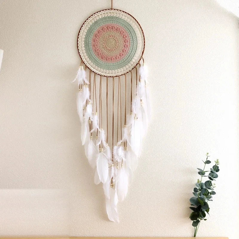 attrape rêve blanc - disque ajouré pastel et plumes blanches près d'un eucalyptus