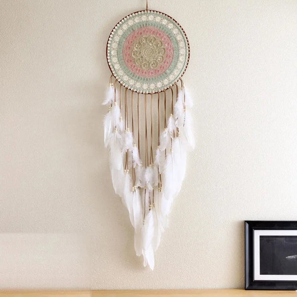 attrape rêve blanc - disque ajouré pastel et plumes blanches accroché à un mur crème