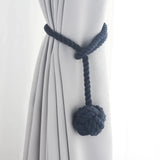 Embrasse rideau boule en corde de coton - coloris bleu marine, boule de coton nouée sur un rideau gris