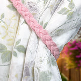 Embrasse rideau tressée en coton rose pâle drapée autour d'un voilage blanc à motif floral, jardin flou