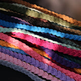 Plusieurs embrasses de rideau tressées en coton de couleurs variées, rose, bleu, vert, violet et marron, empilées