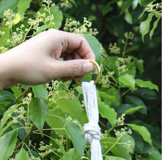 Gros plan sur l'anneau métallique d'un porte-plante en macramé, tenu à la main