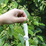 Gros plan sur l'anneau métallique d'un porte-plante en macramé, tenu à la main