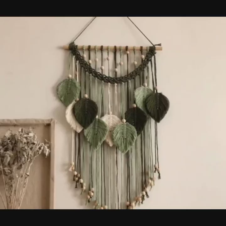 Tenture murale macramé Arcelle vert profond suspendue à un mur beige