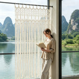 Rideau macramé bohème - devant une grande fenêtre ouverte sur un lac, une femme lit