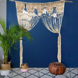 Rideau macramé papillon Orven suspendu barre bois, mur bleu nuit, palmier et pouf marocain