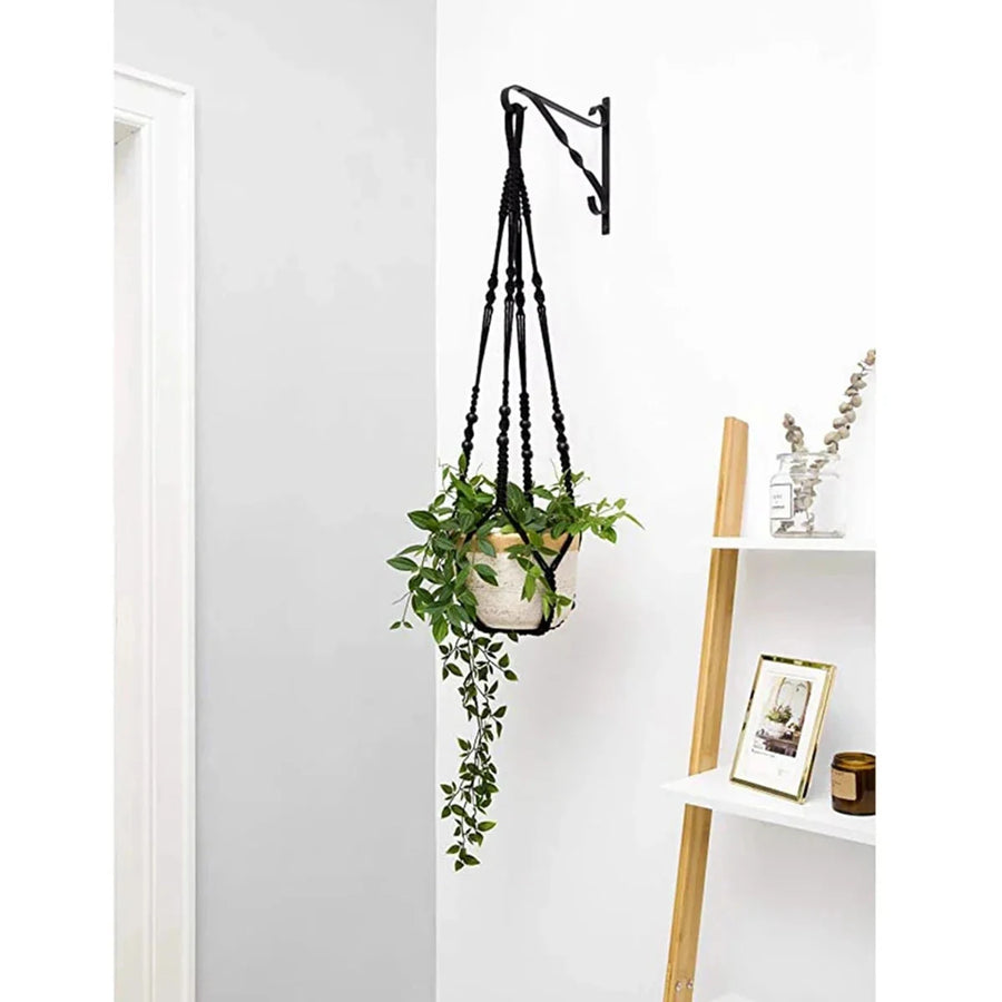 Support pot de fleurs suspendu macramé - coloris noir avec une plante retombante près d'une étagère blanche