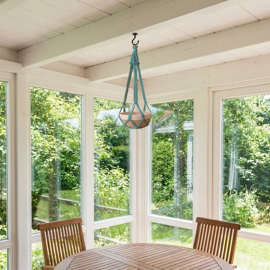 Suspension plante macramé - coloris bleu canard accrochée à un crochet sous les poutres blanches d'une véranda ouverte sur le jardin