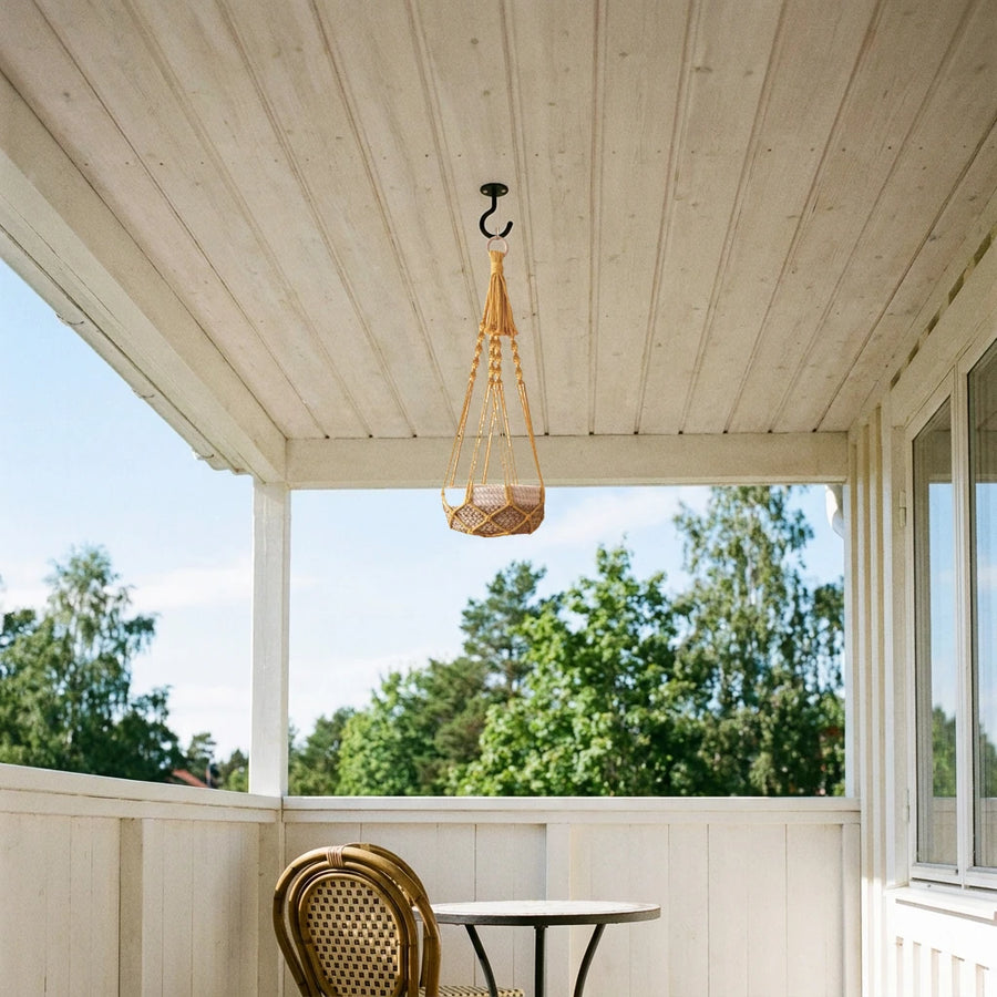 Suspension plante macramé corde de coton - modèle jaune moutarde accroché à un crochet sous le plafond en bois d'un balcon couvert, en été