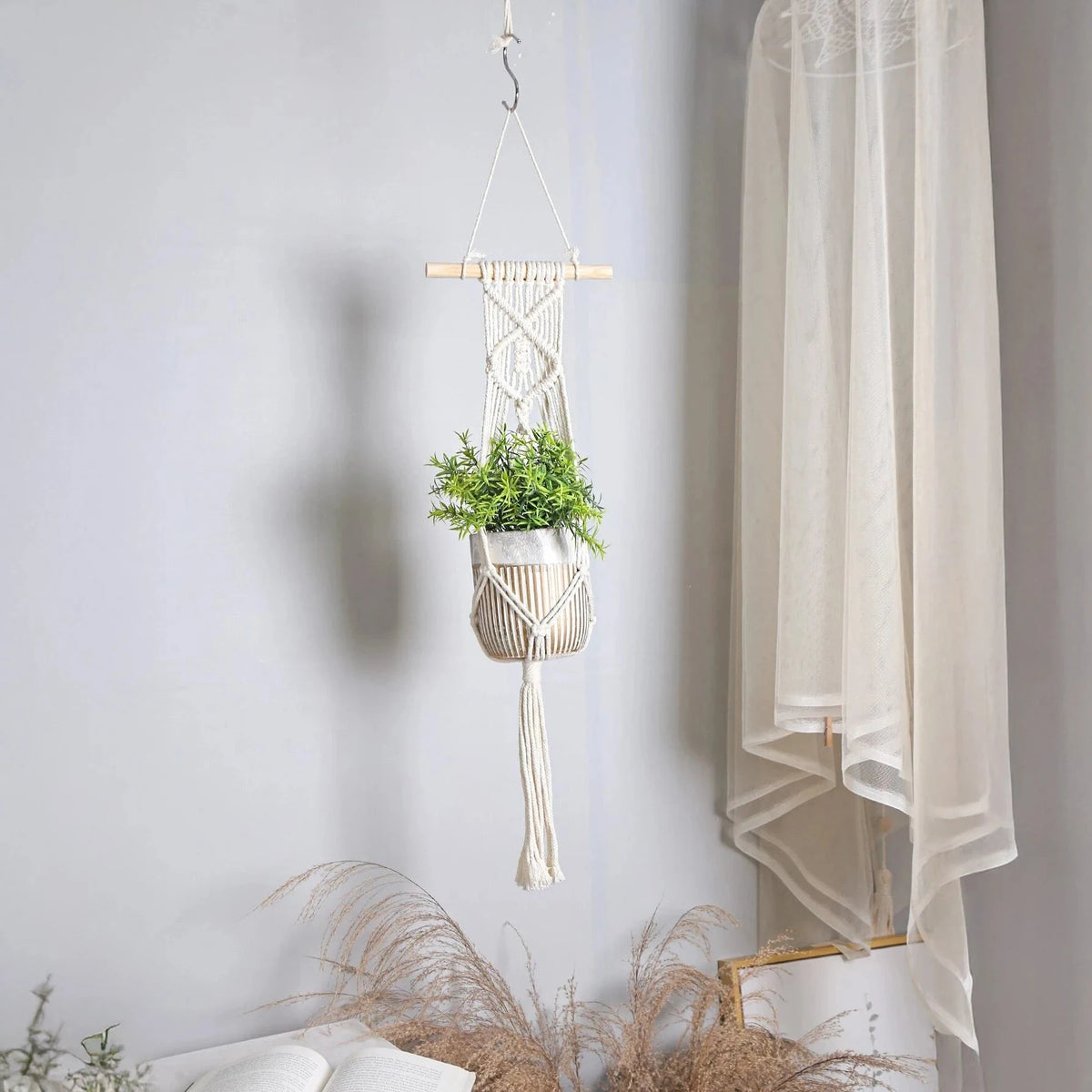 Suspension pot de fleurs macramé - modèle à bâton de bois accroché dans un salon près d'un rideau voilage