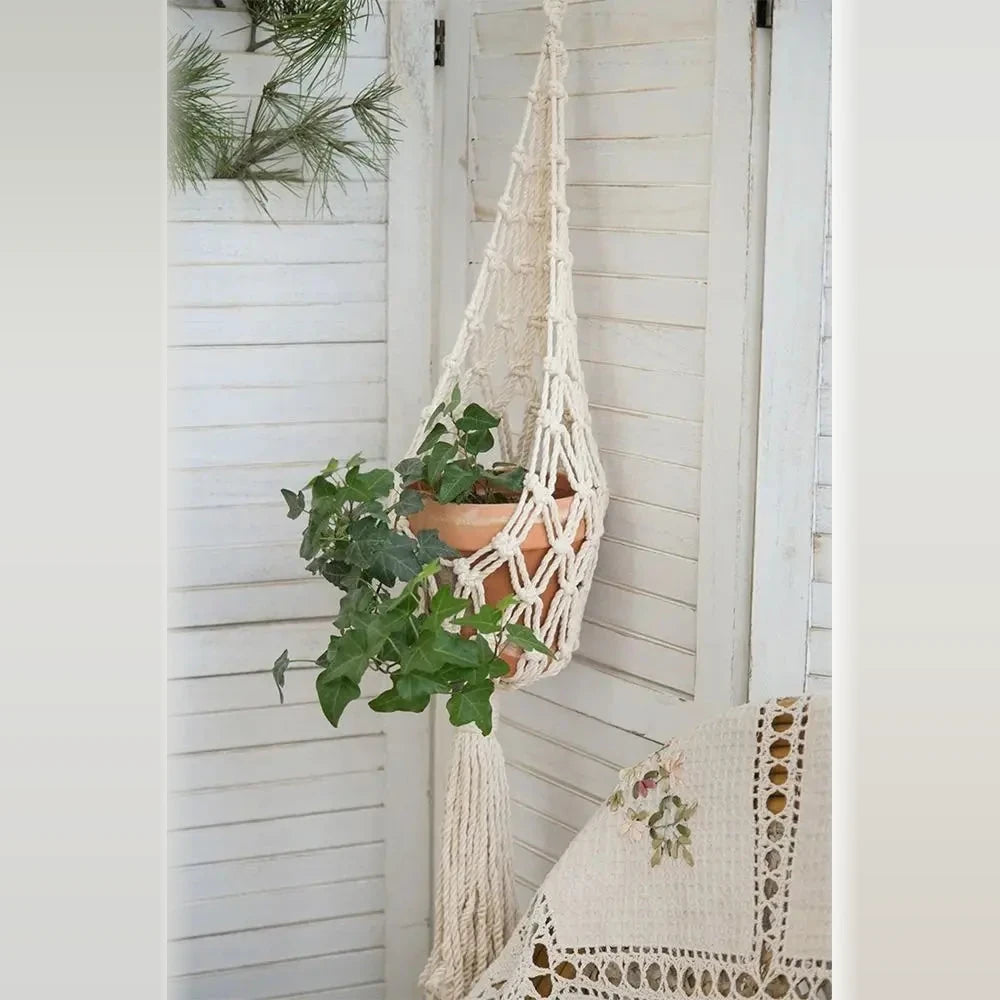Suspension pour plantes macramé - modèle filet à gland devant un paravent blanc, pot avec lierre