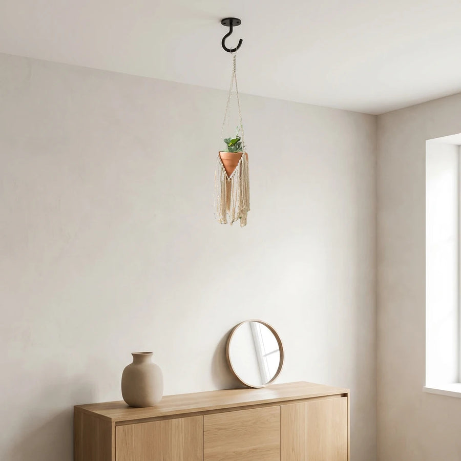 Suspension pour plantes macramé - modèle à franges dans un coin de salon près d'un buffet en bois et d'un miroir rond